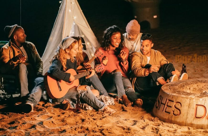 friends playing instruments at a beach campfire