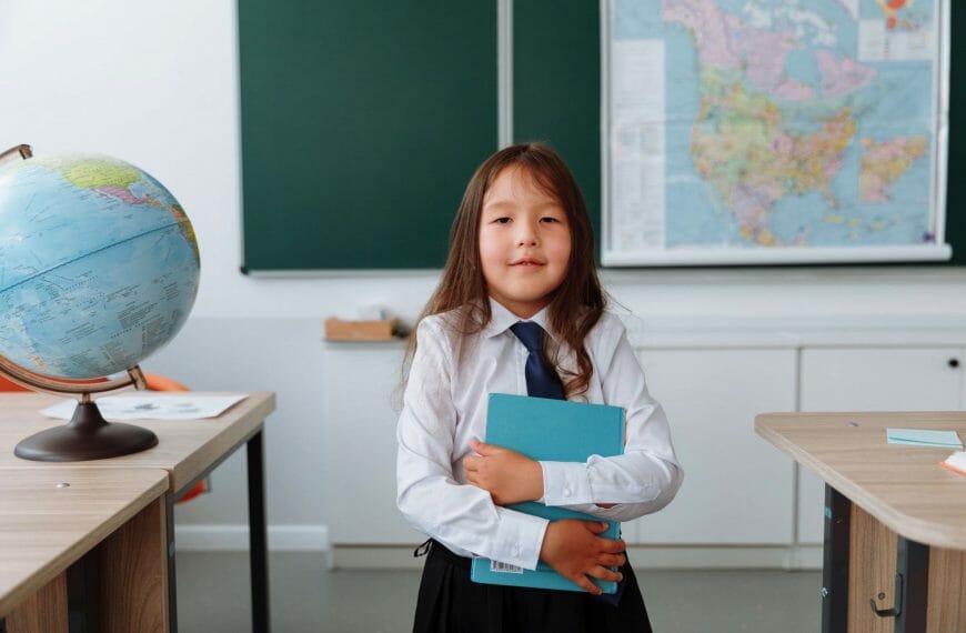 Learn - a young student clutches a blue notebook against herself in a geography classroom