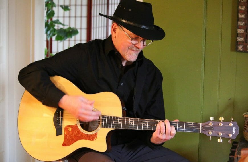 Stan Stewart playing a guitar while wearing a cowboy hat