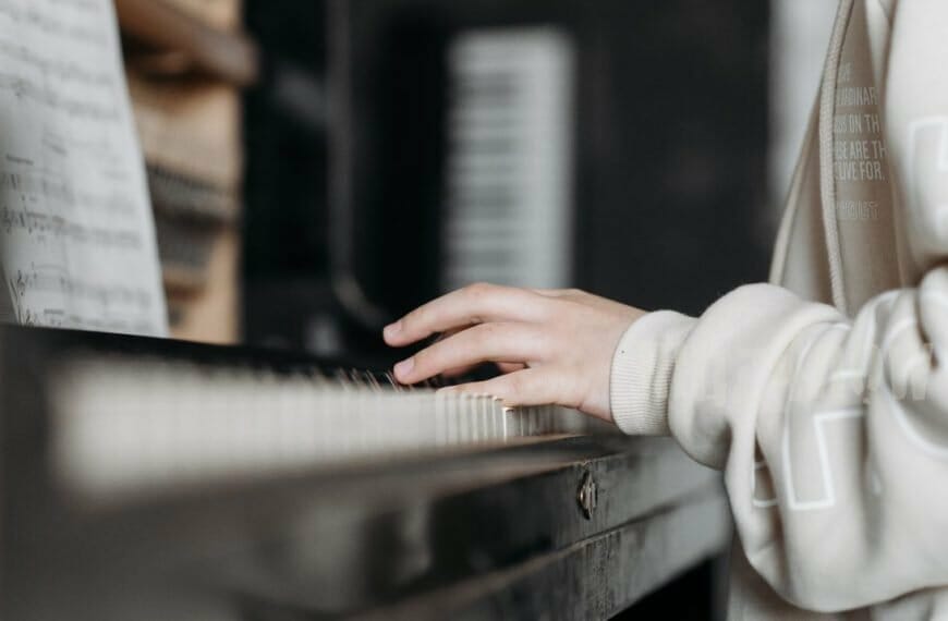 A person wearing a sweater plays a black piano - musical influencers