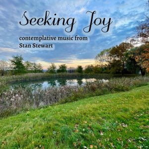 Clouds and autumn foliage are mirrored back by a pond in the cover for "Seeking Joy" contemplative music by Stan Stewart
