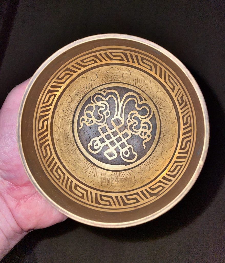 A Tibetan meditation singing bowl in a person's hand.