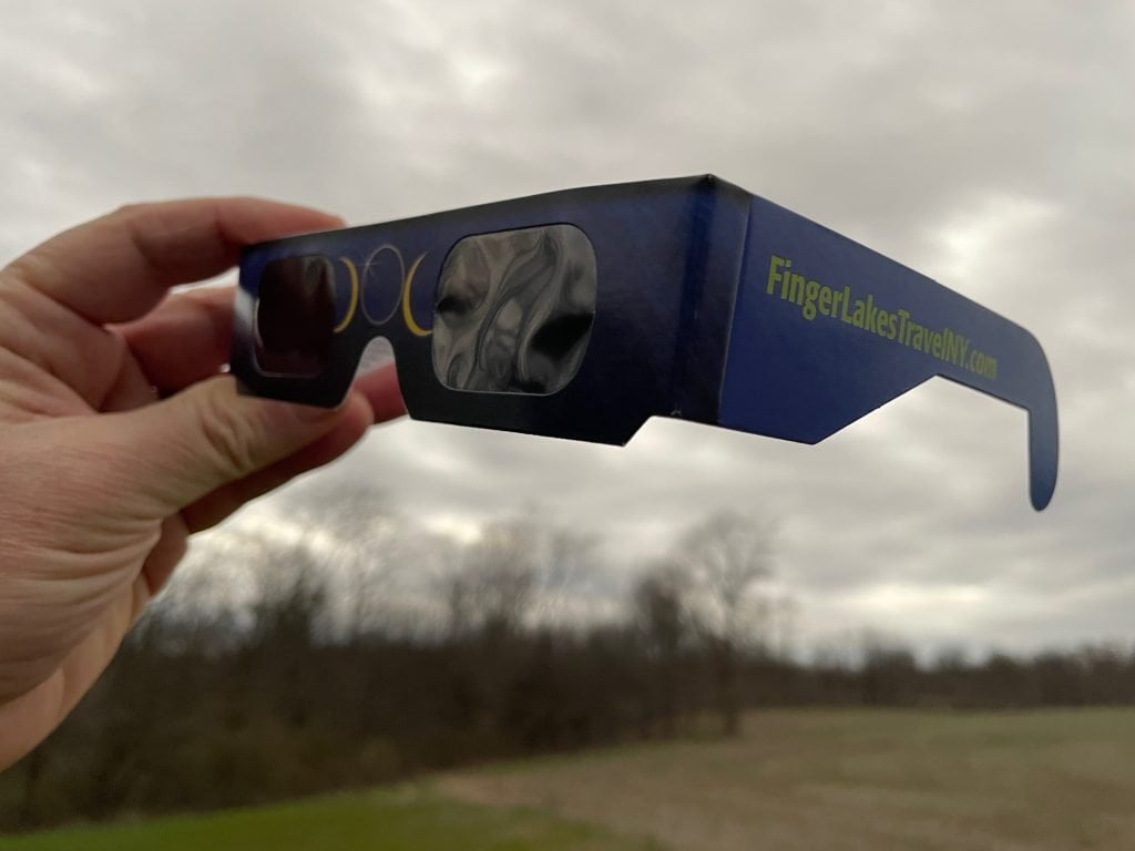 Eclipse protective glasses with "Finger Lakes Travel NY" printed on the side.