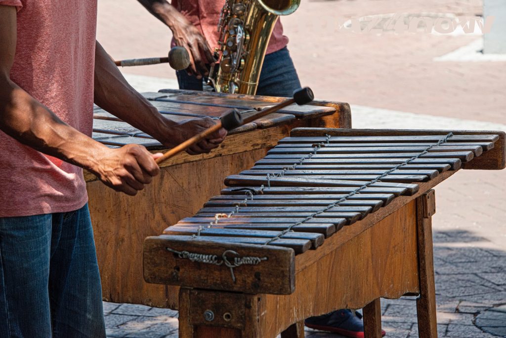 A marimba and a saxophone player give a happy vibe as they play on a street corner