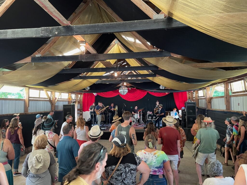 Festival goers listen to a band playing in a rustic cabaret.
