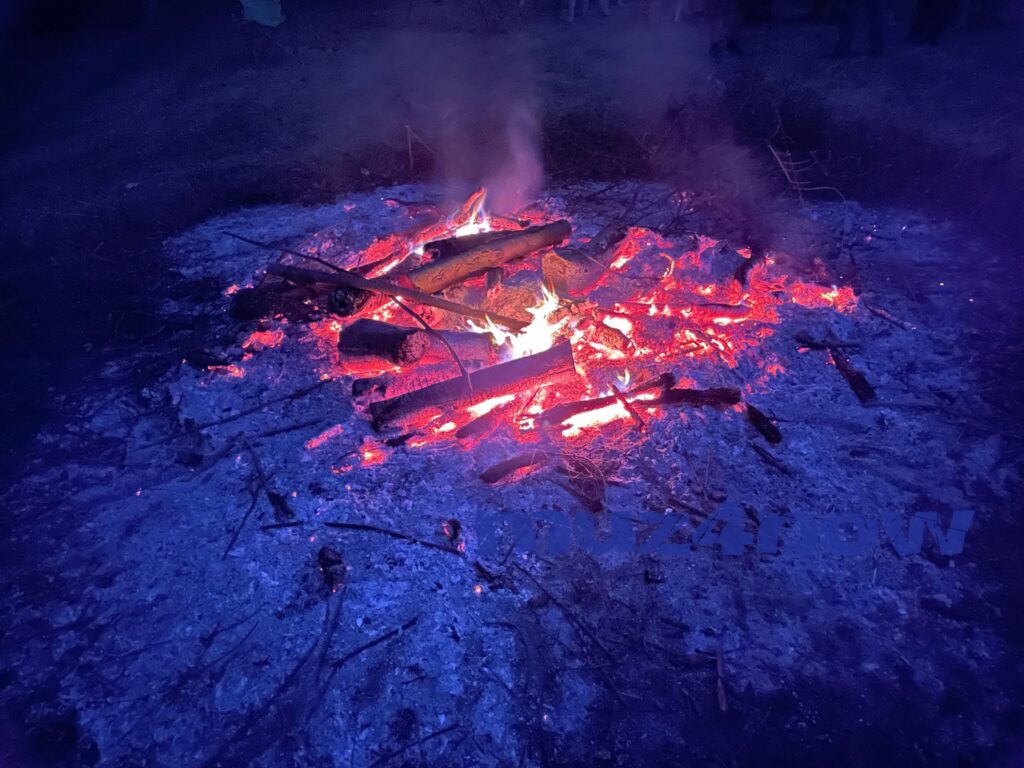 A fire with bright, hot coals burns in the night.