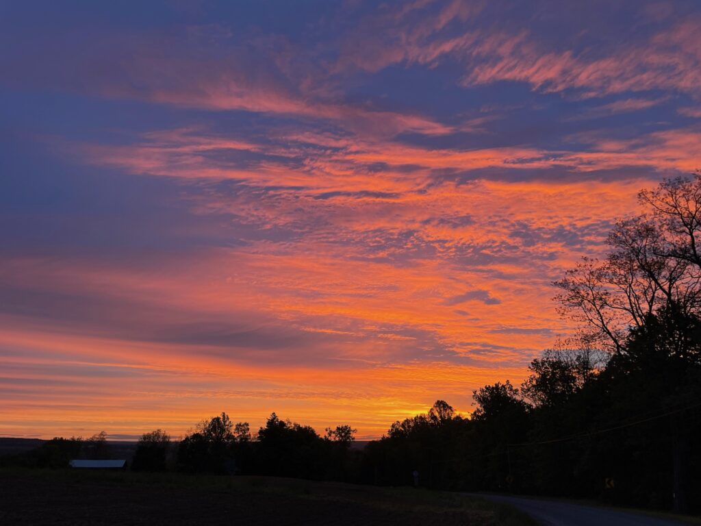 The sunrise turns the early morning sky bright orange with gold and dark blue accents.