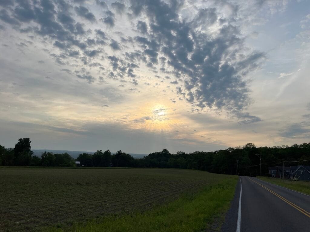 The sun is rising behind heavy cloud cover. Some of the clouds seem to be speckled and closer to us.