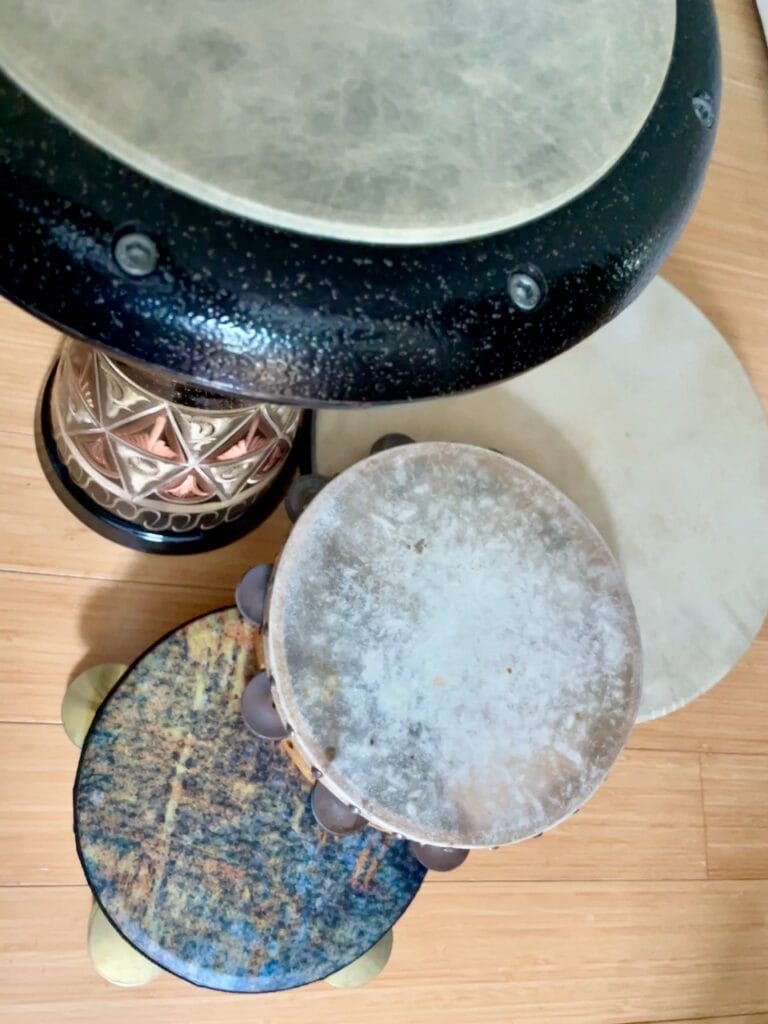 An array of four handdrums: copper darbuka, colorful riqq, aged tambourine, and a frame drum.
From the photo session for Ritual Escape suite.