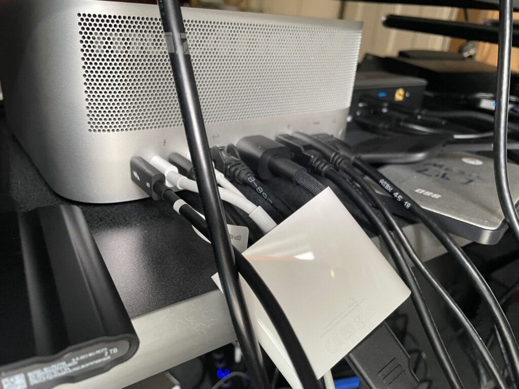 A Mac Studio computer with all of the connections on the back connected. In other words, there are lots of cables hanging out of this computer.