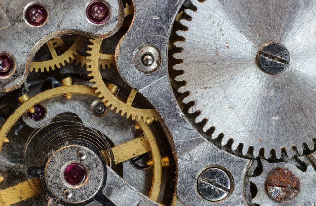 Representing generative AI, a variety of metal cogs mesh together to make a mechanism.