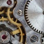 Representing generative AI, a variety of metal cogs mesh together to make a mechanism.