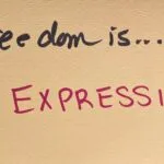 "Freedom is... EXPRESSION!" written in felt-tip marker on a beige index card. Written as a prompt for a piano improvisation concert.