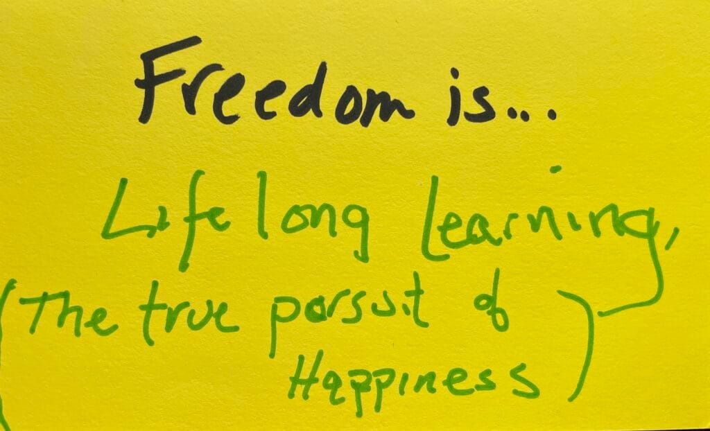A bright yellow index card with these words printed using a felt-tip marker: "Freedom is... Lifelong learning (the true pursuit of happiness)"
Written as a prompt for a piano improvisation concert.