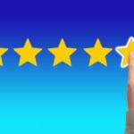 A hand with the pointing finger on the 5th of five stars as if rating in reviews.