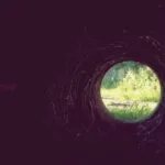 The light at the end of the pipeline reveals green vegetation.