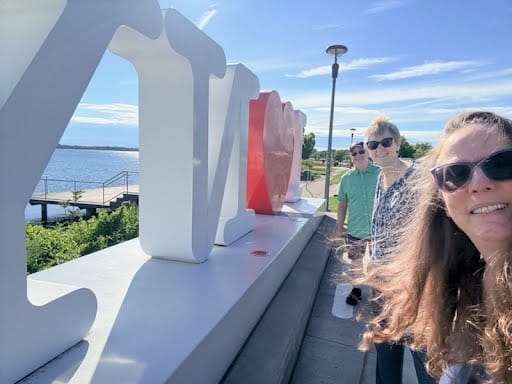 Three people standing next to the (back of) an I ❤️ NY™️ sign. They are about to go to live performance workshops.