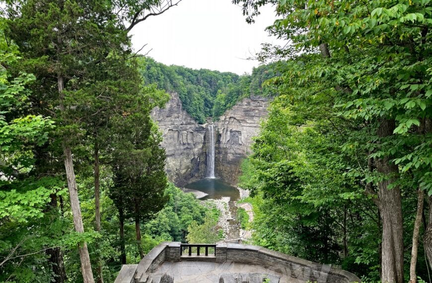 A tall waterfall pours down a grey rock face. All around the rocks are deep, green forests. Simple pleasures.