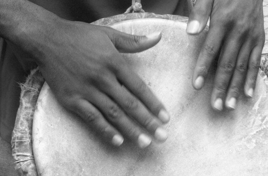 Someone has both of their hands on a large drum head. Drums and other instruments vary with our culture.
