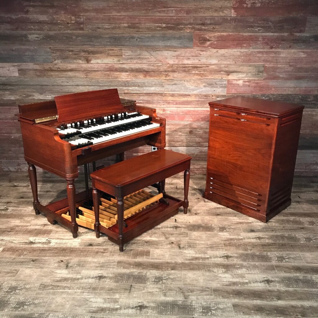A Hammond B3 electronic organ and Leslie speaker in mint condition captured against a wooden room. You can almost hear the sound...
Found at https://chicagoorgancompany.com/products/hammond-b3-organ-1957-leslie-122-speaker-red-mahogany