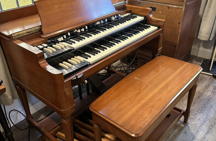 A Hammond B3 with wooden bench and Leslie speaker is next to a window. Found at https://www.reddit.com/r/hammondorgan/comments/186f7l6/my_new_acquisition_today_a_pristine_b3_with/